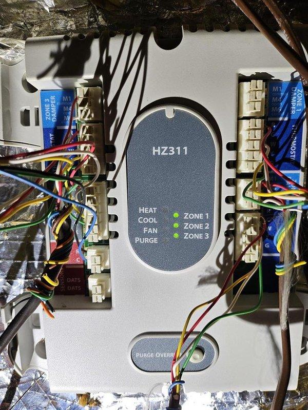 Responded to service call for multi-zone HVAC system where one zone was not cooling properly and heating system was inadvertently activating when zone was shut off. Upon arrival, inspected HZ311 zone control panel and verified system operation across all three zones. Found zone control board functioning with proper LED indicators, though zone damper operation required verification. Examined zone wiring connections at terminal strips and confirmed secure terminations of all thermostat and damper control wires. Tested system cycling through heat, cool, and fan modes to isolate the cross-control issue between cooling and heating functions.

Inspected ductwork in attic space and documented condition of zone dampers and associated wiring. Noted deteriorated duct insulation with multiple tears and holes, which could impact system efficiency but was not directly related to the reported zone control malfunction. Traced control wiring from zone panel to affected zone damper to identify any shor
