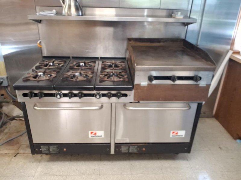 Successfully installed new gas line connection to commercial-grade six-burner kitchen range with griddle and dual oven compartments. Routed black iron pipe through structural framework, secured with appropriate clamps and brackets, and made final connection to appliance per code requirements.