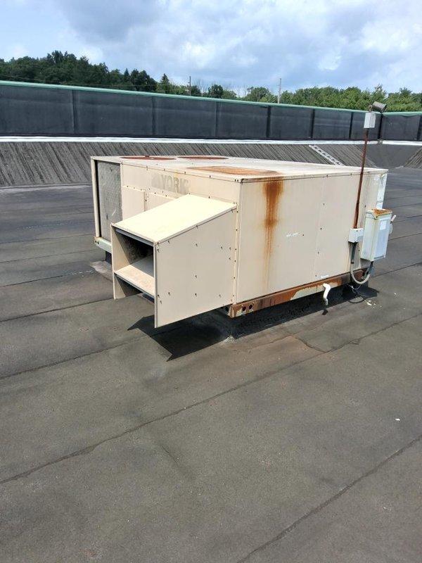 Conducted comprehensive assessment of two existing rooftop HVAC units for replacement estimate. Both York RTUs showed significant age-related deterioration including extensive rust staining, weathered exterior panels, and corroded base components. Documented current equipment conditions through detailed photography, noting unit specifications, electrical disconnects, and mounting configurations. Evaluated rooftop membrane condition, curb adapters, and accessibility requirements for future replacement work.