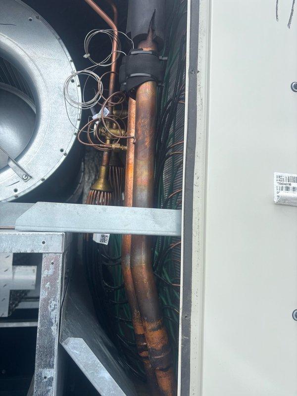 Conducted walkthrough inspection of third floor HVAC unit to investigate reported water leak and verify fan motor operation. Accessed unit interior and documented condition of internal components including blower assembly, refrigerant lines, and evaporator coil. Observed significant oxidation and discoloration on copper piping indicating age and environmental exposure. Confirmed presence of moisture accumulation within unit chamber with visible condensation on surfaces and metallic insulation material. Identified water pooling on chamber floor with debris present. Documented finned coil assembly condition and overall component arrangement for assessment. Obtained measurements and photographic documentation for curb adapter fabrication requirements to facilitate future equipment modifications.