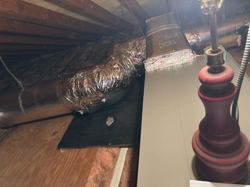 Completed comprehensive ductwork modification in attic space to improve system airflow and performance. Removed existing plenum box and installed new 4-foot insulated duct section. Relocated existing round duct feeding living area for improved air distribution. Installed new 10-inch supply trunk line and reconnected three existing 6-inch branch lines to the new trunk. Installed airtight collars with dampers on main trunk lines and curved airtight dampers on all three 6-inch supply branches for proper air balancing.

Addressed critical drainage issue where condensate drain line had disconnected from top of drain pan, causing water to flow down around suction line and into control panel cavity. Water was found running through thermostat wire jacket. Reconnected and secured drain line to prevent further water intrusion and potential electrical damage.

Performed system performance testing using digital manifold and temperature probes. Measured and compared static pressure readings before 