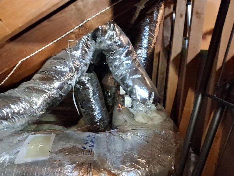 Conducted attic inspection and documentation of existing HVAC ductwork system to obtain measurements for complete duct replacement estimate. Photographed flexible aluminum ductwork showing significant deterioration including damaged insulation wrapping, visible staining, tears in vapor barrier, and evidence of previous repairs with tape and patching materials. Documented duct routing, configuration, and spatial constraints within confined attic space for accurate material takeoff and labor assessment.