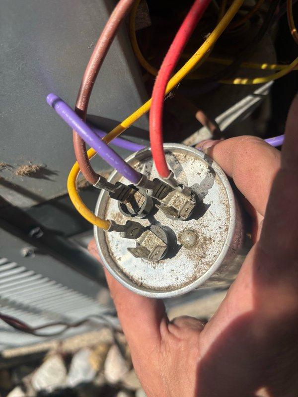 Responded to no cooling complaint with unit blowing warm air. Upon inspection, identified failed dual run capacitor with visible corrosion and deterioration at terminal connections. Removed defective capacitor and replaced with new component, restoring proper compressor and condenser fan motor operation. System tested and confirmed cooling properly.