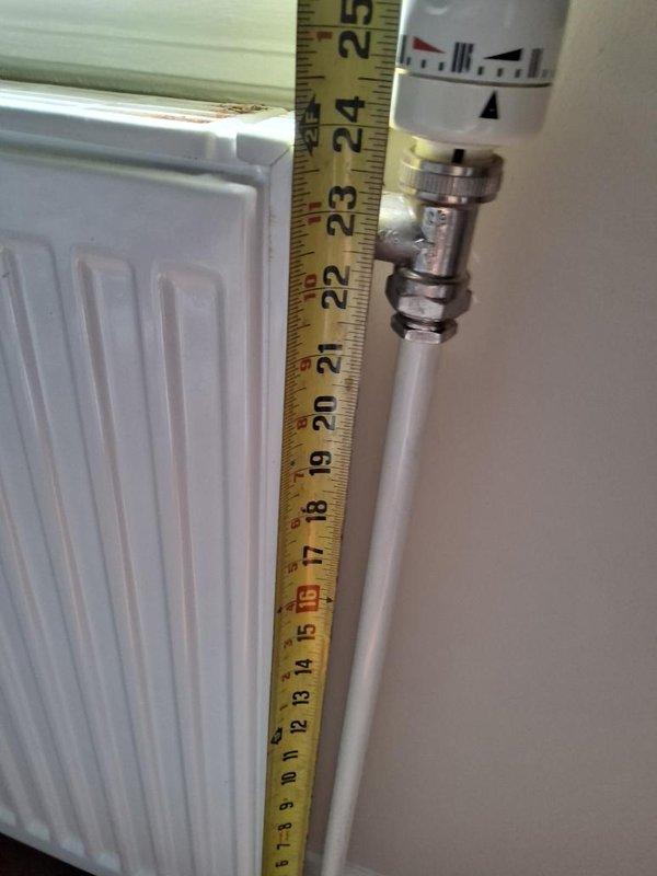 Completed on-site assessment for radiator replacement project. Documented existing white panel radiator with thermostatic valve, measured unit dimensions, and evaluated mounting location and wall conditions. Photographed current installation including valve assembly, supply piping, and floor-to-ceiling measurements to prepare accurate replacement estimate.