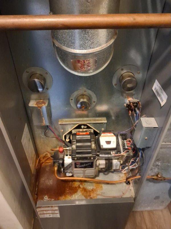 Completed annual maintenance and tune-up on oil-fired furnace system. Performed comprehensive inspection of Beckett burner assembly, cleaned and tested all components, verified proper operation of motor and electrical connections, and checked copper fuel line connections for integrity. Noted rust staining present on interior floor pan indicating previous moisture exposure; verified current system operation is normal with no active leaks detected.