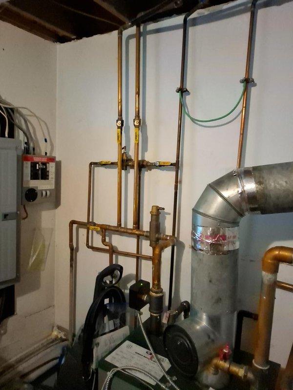 Conducted on-site assessment for oil-to-gas boiler conversion project scheduled through New Jersey Natural Gas utility program. Evaluated existing oil-fired heating system including current boiler configuration, copper piping distribution network, circulator pumps, electrical service capacity, and venting infrastructure. Documented existing mechanical room layout with attention to electrical panel location, hydronic piping arrangements with multiple zone valves and manifolds, and current oil burner control systems including Riello burner assembly and emergency shut-off switches. Photographed HVAC ductwork connections and existing flue pipe routing to determine gas boiler installation requirements and necessary modifications for proper venting and combustion air supply.