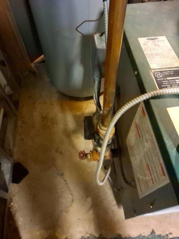 Responded to a no-heat call on an aged cast iron boiler and inspected the unit, flue, and associated piping and valves. Documented heavy corrosion and oxidation on the copper supply piping and isolation valve, along with rust and mineral deposits at the base of the piping, indicating long-term leakage and age-related deterioration. The boiler's condition and component wear were noted as the cause of the heat loss, with replacement recommended to restore reliable heating.