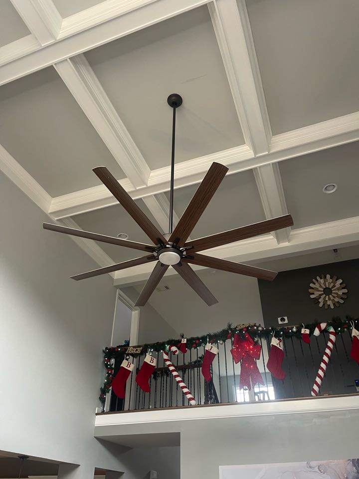 Electrician is installing a large ceiling fan on high ceilings 