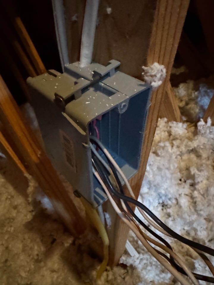 Electrician rewiring outlet in attic. 
