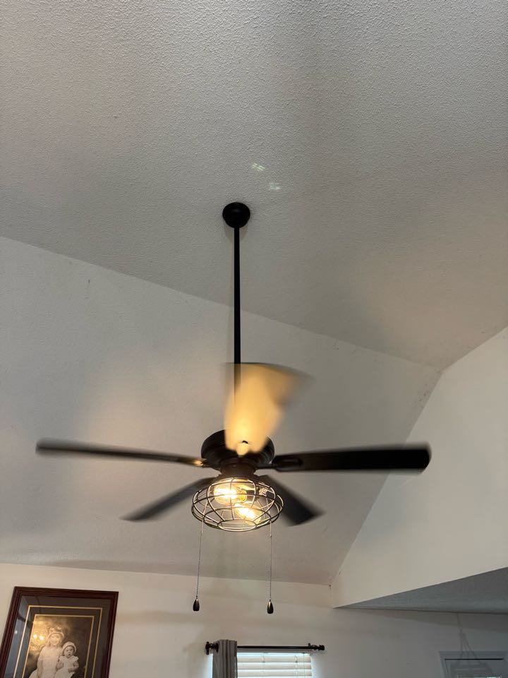 Electrician installing ceiling fan in living room