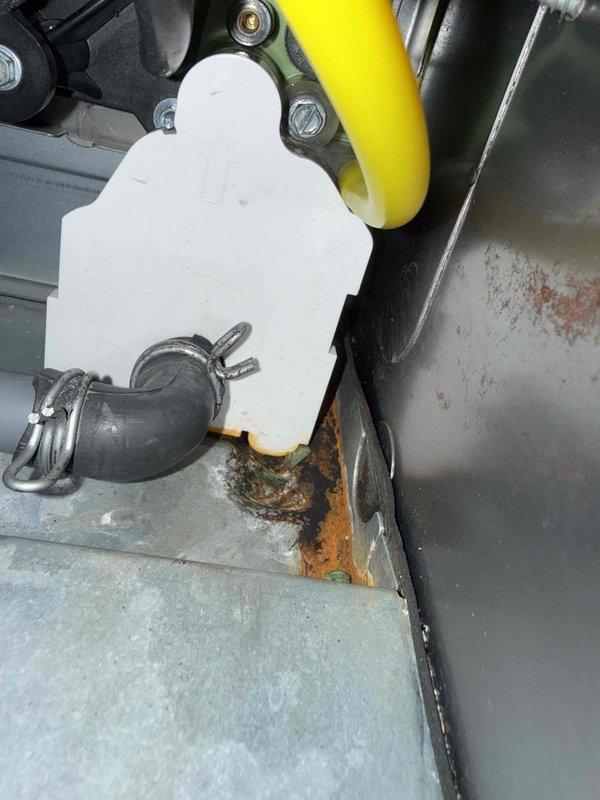 Diagnosed water leak under 8-year-old basement furnace connected to humidifier system. Inspection revealed significant corrosion and rust formation at drain connection point, with deterioration visible at the humidifier reservoir connection to metal surface. Replaced damaged drain hose and connection components to resolve the leak while maintaining proper system operation.