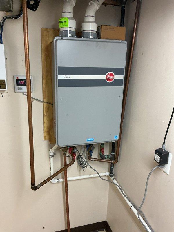 Performed comprehensive descaling maintenance on wall-mounted Rheem tankless water heater. Flushed system to remove mineral buildup, inspected all connections and verified proper venting through PVC pipes. Confirmed unit operating at 130° temperature setting with all valves functioning correctly.