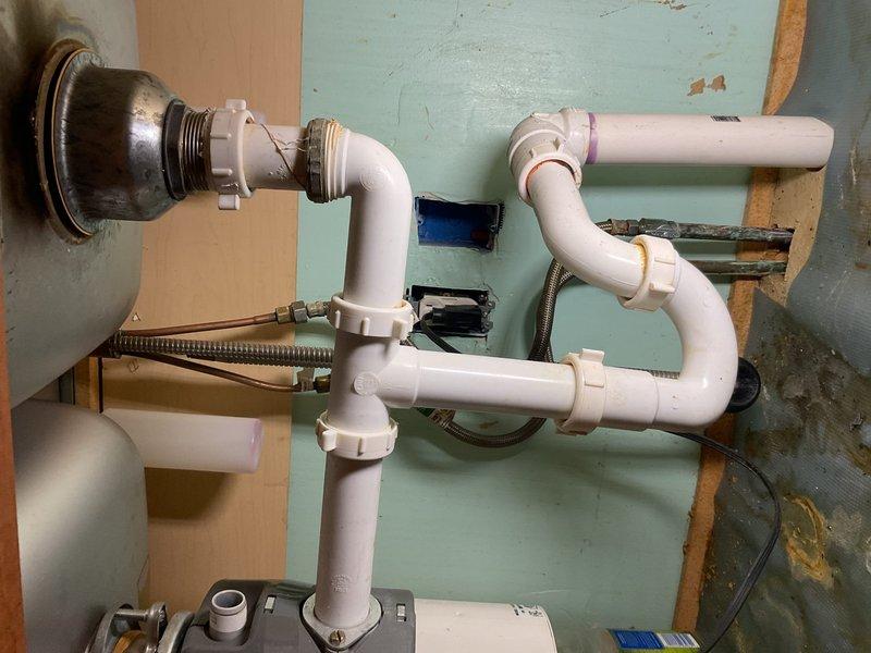 Inspected copper piping under sink for reported leak. Examined P-trap configuration and PVC connections which showed signs of wear. Identified and repaired leak at connection point between drain flange and wall. Verified proper drainage function and confirmed no further water leakage from the plumbing system.