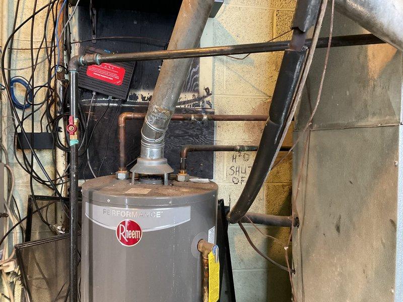 Responded to service call for non-functioning Rheem Performance commercial water heater (approximately 12 years old) located in boiler room. Upon inspection, identified ignition failure in the tank system. Performed diagnostic assessment, documented condition with photos of the installation including ductwork, venting, and copper pipe connections.