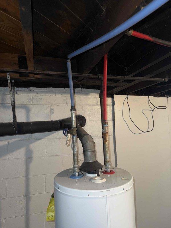 Responded to no hot water complaint for 10+ year old tanked water heater located in basement. Diagnostic inspection revealed water leaking from tank base with visible corrosion around bottom ventilation panels. Replaced failed water heater with new unit, including proper connection of hot/cold water lines and exhaust venting, restoring hot water service to residence.
