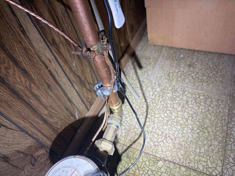 Addressed City of Warren electrical violations by installing proper ground rods below grade, cleaning and securing water ground connections to pipe, installing correctly sized overcurrent protection for #12-#14 circuits, and ensuring all NMB cable jackets terminate at least 1/4" inside the panel. Documentation photos show deteriorated wiring insulation requiring replacement and proper water ground connection installation at the copper plumbing system.