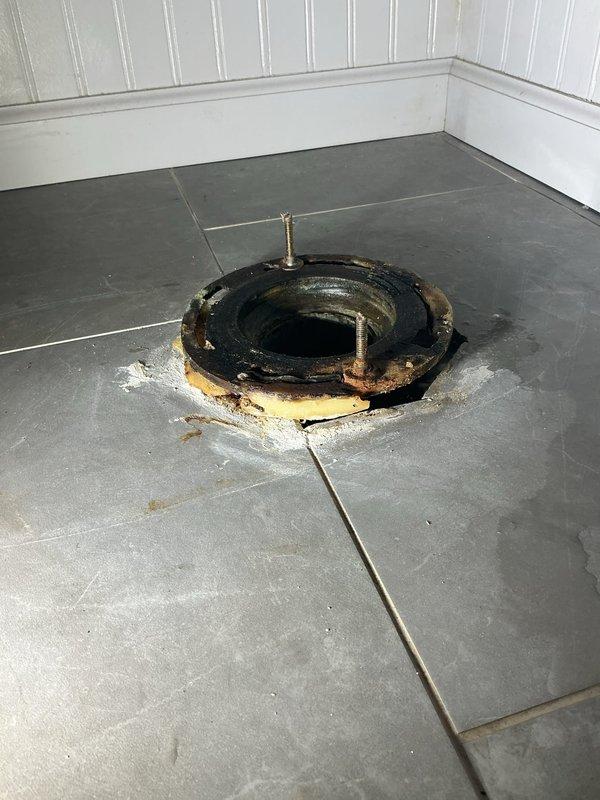 Performed diagnostic assessment on 2nd floor bathroom toilet. Inspected existing toilet flange, finding significant corrosion and deterioration with degraded wax ring. Removed old flange and installed new white plastic toilet flange properly secured to the gray tiled floor, preparing the area for toilet reinstallation.