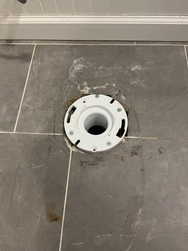 Performed diagnostic assessment on 2nd floor bathroom toilet. Inspected existing toilet flange, finding significant corrosion and deterioration with degraded wax ring. Removed old flange and installed new white plastic toilet flange properly secured to the gray tiled floor, preparing the area for toilet reinstallation.