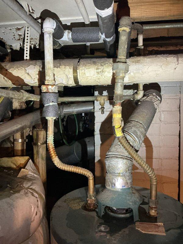 Performed diagnostic assessment of water valve and gas line issues. Inspected aging plumbing infrastructure including corroded copper pipes, deteriorating insulation, and brass valve in utility area. Documented condition of hot water tank connections and surrounding plumbing system to prepare detailed estimate for necessary repairs to address water leak and gas line reconfiguration.