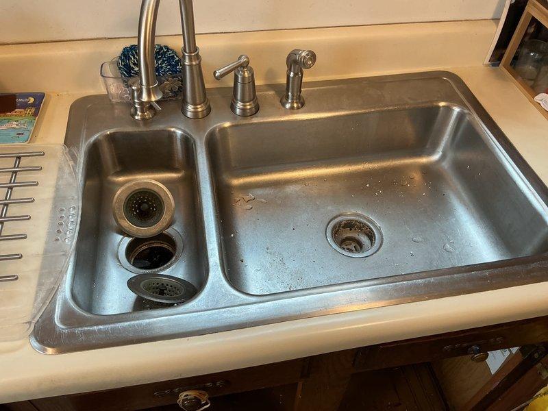Responded to service call for kitchen sink clog causing backup issues. Inspected dual-basin stainless steel sink and PVC P-trap assembly. Successfully cleared blockage in drain line that was causing recurring backup problem previously reported by customer.