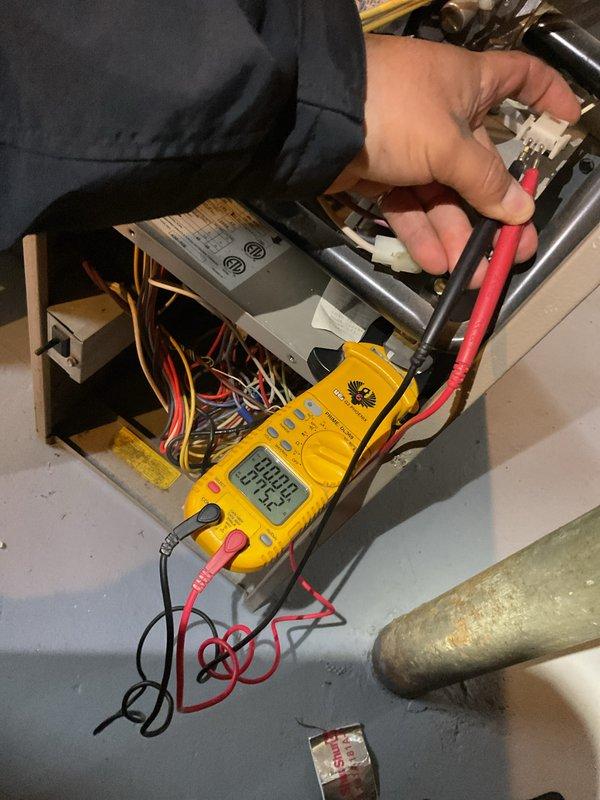 Performed city certification inspection on furnace over 10 years old located in basement. Conducted electrical testing with multimeter on control board, verifying proper voltage readings (0.642). Inspected and tested humidifier, thermostat, and hot water tank as part of comprehensive system evaluation. Unit appears to be in normal operating condition with no visible damage or deterioration.