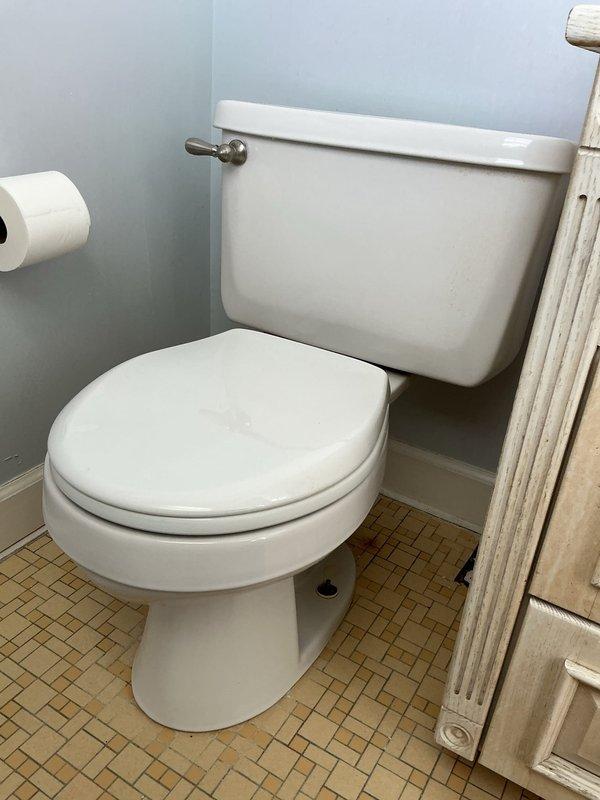 Responded to service call regarding water stains on living room ceiling. Diagnostic inspection revealed toilet tank leaking at the bowl connection, evidenced by visible brownish water stains and mineral deposits trailing from the tank-to-bowl seal. Recommended tank-to-bowl gasket replacement and complete toilet rebuild to resolve the leak causing ceiling damage.