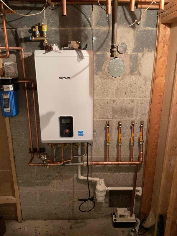 Successfully installed a Navien combi-boiler system with complete copper piping network, including proper gas line connections with safety valves. System includes integrated water filtration unit, condensate pump, and all necessary gauges and valves for optimal operation, professionally mounted on concrete block wall with Energy Star certified equipment.