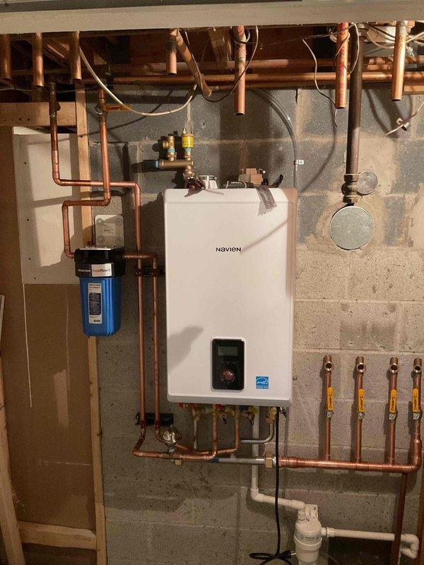 Successfully installed a Navien combi-boiler system with complete copper piping network, including proper gas line connections with safety valves. System includes integrated water filtration unit, condensate pump, and all necessary gauges and valves for optimal operation, professionally mounted on concrete block wall with Energy Star certified equipment.