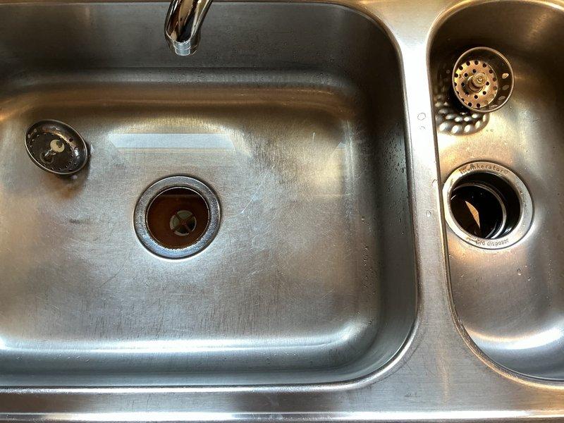 Installed new stainless steel double-basin kitchen sink with InSinkErator garbage disposal, resolving previous drainage issues. Replaced worn bathroom tub faucet handle that had significant wear and corrosion on the valve plate.