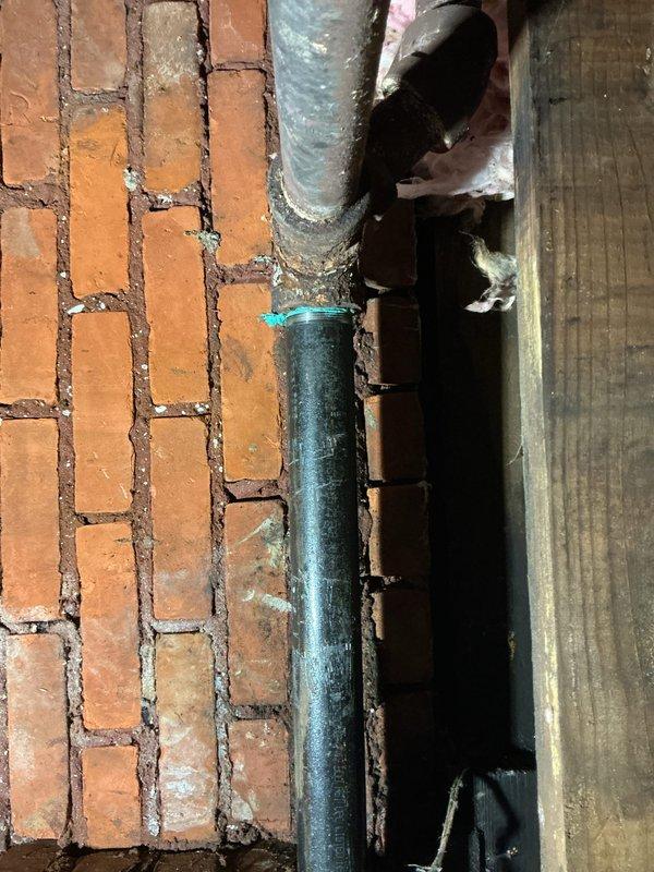 Completed steam line repairs in confined structural space, addressing deteriorated sections where insulation was compromised. Installed new vertical cast iron pipe with proper connections against brick wall, securing all components with appropriate fasteners and ensuring system integrity for continued operation.