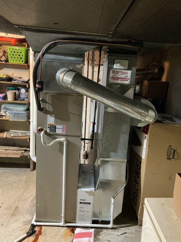 Performed diagnostic evaluation on 10-year-old furnace system located in basement due to complaint of blowing cold air. Inspection revealed failed secondary heat exchanger. Provided comprehensive replacement estimate for new furnace system, documenting existing installation configuration and exterior venting/drainage components for proper system matching.