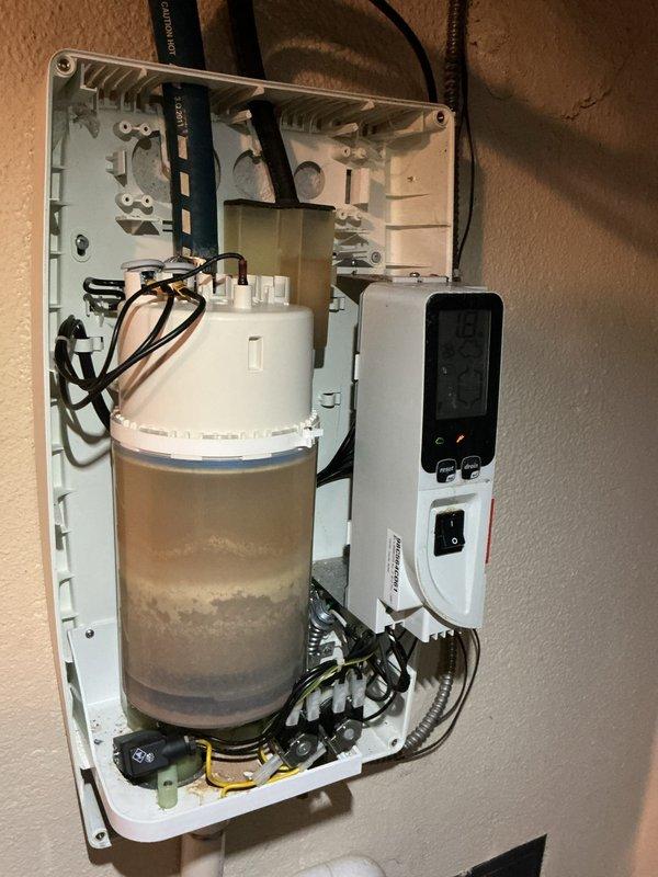 Performed service on residential steam humidifier showing sediment buildup in the water container. Inspected system components including digital control panel (reading 5.1A) and drainage functionality. Cleaned accumulated mineral deposits and verified proper operation of the humidification system to resolve reported humidity issues.