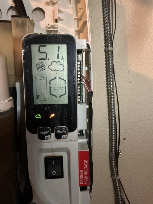 Performed service on residential steam humidifier showing sediment buildup in the water container. Inspected system components including digital control panel (reading 5.1A) and drainage functionality. Cleaned accumulated mineral deposits and verified proper operation of the humidification system to resolve reported humidity issues.