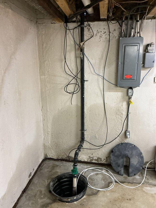 Successfully completed replacement of a failing sump pump system in basement utility area. Removed old unit showing significant mineral buildup, corrosion, and standing water with sediment. Installed new sump pump with proper electrical connections and verified system operation through the existing PVC discharge line.