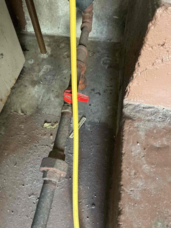 Responded to customer complaint of boiler cycling without producing heat. Inspection revealed significant corrosion and deterioration of valve components, particularly a green valve body with extensive rust and streaking indicative of moisture damage. Noted substantial corrosion along plumbing pipes in utility room with compromised connections that prevented proper system operation.