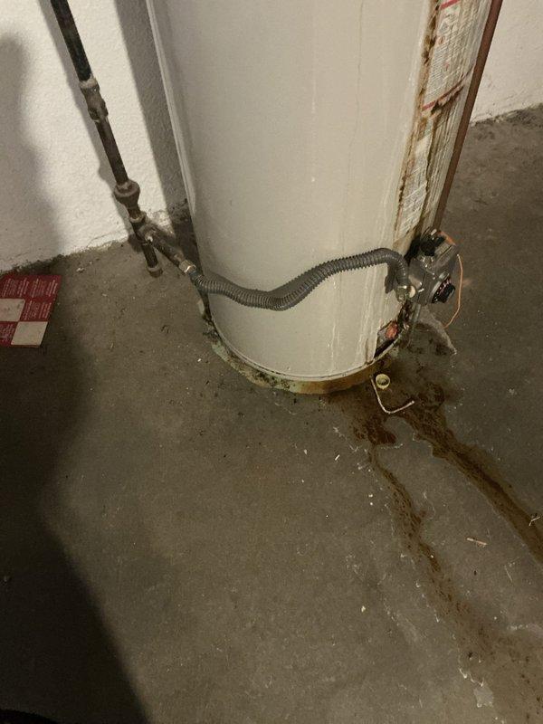 Replaced 40-gallon A.O. Smith ProMax water heater in basement that showed significant rust damage and leakage evidenced by water stains on concrete floor. Installation included proper venting connections, supply line hookups, and installation of required drip pan to prevent future water damage.
