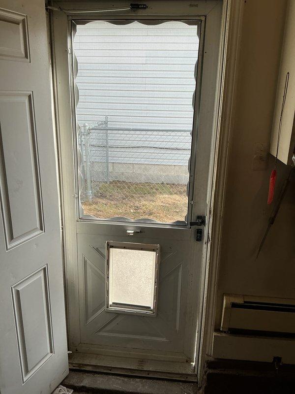 Conducted boiler replacement estimate for a hot water baseboard heating system with natural gas fuel source. Inspected existing thermostat (wall-mounted beige unit with manual dial) and noted access points including rear entrance with pet door. Photos taken of relevant areas to assist with equipment sizing and installation planning.