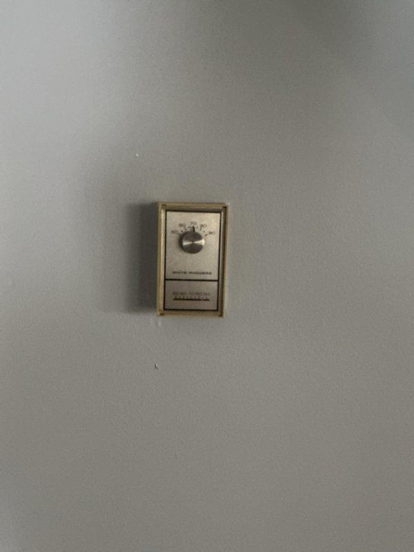 Conducted boiler replacement estimate for a hot water baseboard heating system with natural gas fuel source. Inspected existing thermostat (wall-mounted beige unit with manual dial) and noted access points including rear entrance with pet door. Photos taken of relevant areas to assist with equipment sizing and installation planning.