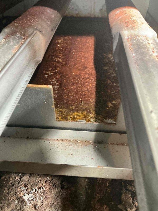 Responded to service call for a steam boiler (approximately 10 years old) displaying error code 57. Diagnosed shorted igniter flame rod grounding to burner. Inspection revealed significant corrosion and scale buildup on heat exchanger tubes and chamber, with extensive rust formation throughout the combustion area. Gas burner operation was verified with proper blue flame pattern after service was completed.