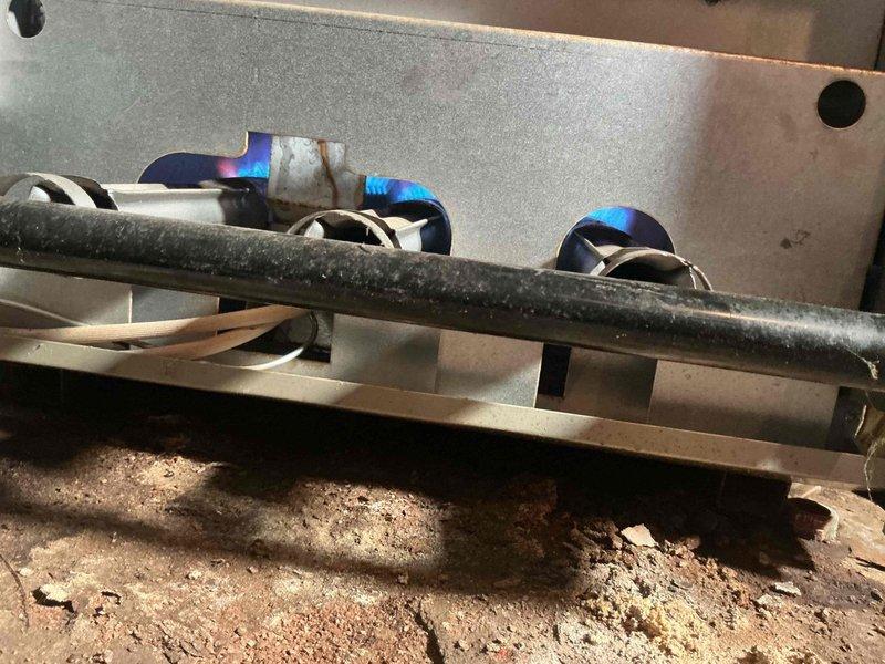 Responded to service call for a steam boiler (approximately 10 years old) displaying error code 57. Diagnosed shorted igniter flame rod grounding to burner. Inspection revealed significant corrosion and scale buildup on heat exchanger tubes and chamber, with extensive rust formation throughout the combustion area. Gas burner operation was verified with proper blue flame pattern after service was completed.