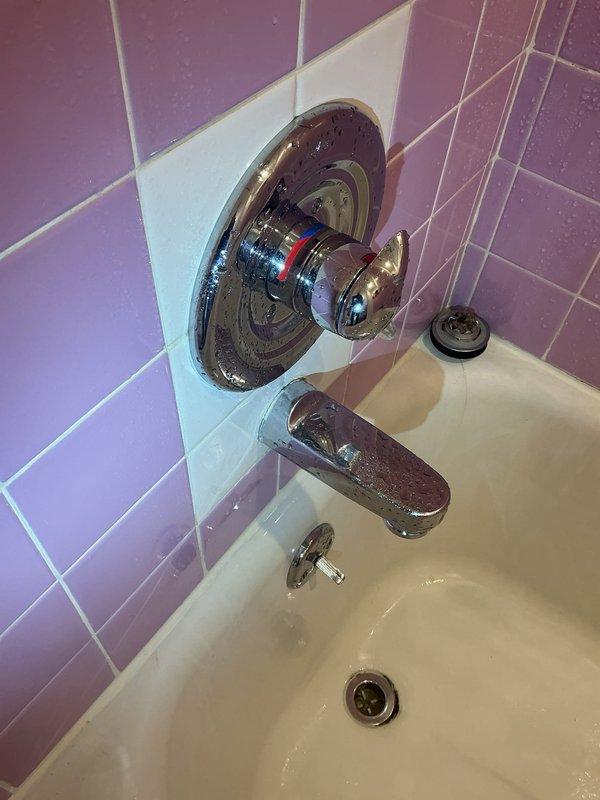 Diagnosed and repaired an intermittent water leak causing discoloration in kitchen ceiling below second-floor bathroom. Upon inspection of the tub access panel, discovered standing water and determined the bathtub faucet/handle assembly was the source of the leak. Replaced faulty valve components in the chrome shower control fixture, eliminating the water infiltration issue that had been occurring for approximately two days.