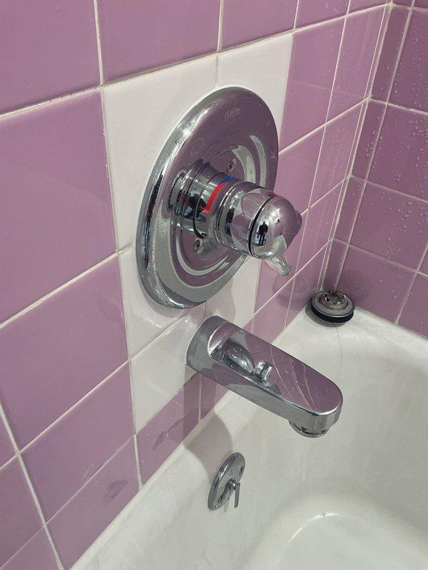 Diagnosed and repaired an intermittent water leak causing discoloration in kitchen ceiling below second-floor bathroom. Upon inspection of the tub access panel, discovered standing water and determined the bathtub faucet/handle assembly was the source of the leak. Replaced faulty valve components in the chrome shower control fixture, eliminating the water infiltration issue that had been occurring for approximately two days.