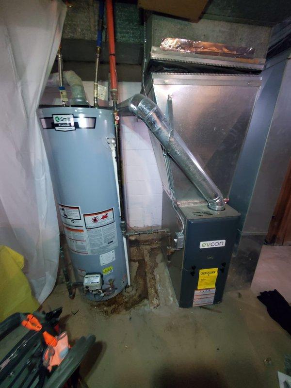 Responded to service call for furnace blowing cool air. Diagnosed issue with Evcon furnace in basement and found water heater in close proximity with visible mineral deposits around connections. Completed necessary repairs to restore proper heating function.