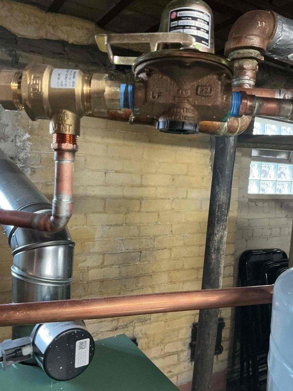 Responded to callback for recently installed boiler system exhibiting a minor water leak. Inspected the installation, focusing on the valve assembly and copper pipe connections where moisture was evident. Tightened brass water valve fittings with blue gaskets to resolve the leak issue.