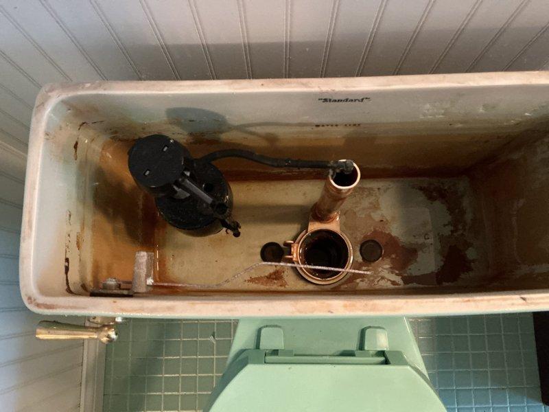 Diagnosed intermittent running toilet in upper bathroom of tri-level home. Inspected internal tank components, which revealed significant mineral buildup and corrosion on the flush valve assembly and copper components. Replaced worn flush valve and flapper to resolve the leak issue, restoring proper water shutoff function.