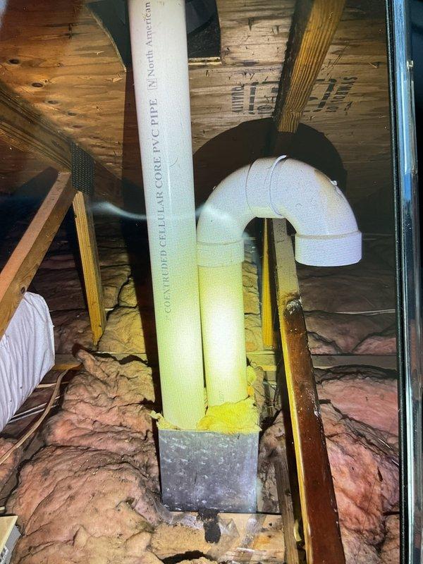 Resolved issue with improperly installed exhaust pipe that was discharging into attic and causing water damage to rafters. Rerouted and properly installed PVC exhaust pipe with appropriate elbow joints and secured with metal strapping. Verified fresh air intake was correctly positioned outside the building as required by manufacturer specifications.