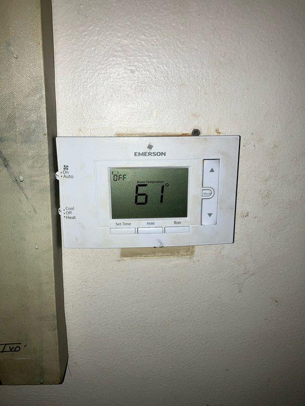 Performed furnace replacement estimate for a 10-year-old unit located in basement. Inspected existing digital Emerson thermostat (currently set to OFF, showing 61°F) and evaluated current HVAC system configuration in relation to water heater installation. Documented system components with photographs for proper replacement specifications.