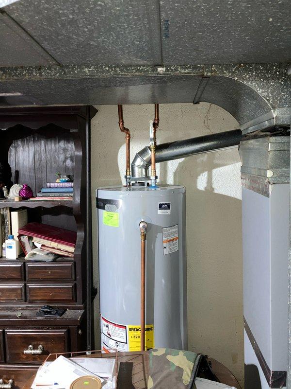 Performed furnace replacement estimate for a 10-year-old unit located in basement. Inspected existing digital Emerson thermostat (currently set to OFF, showing 61°F) and evaluated current HVAC system configuration in relation to water heater installation. Documented system components with photographs for proper replacement specifications.