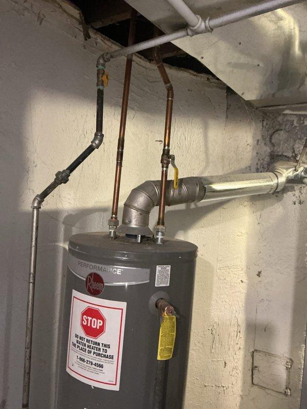 Responded to service call for a Rheem Performance water heater leaking from the bottom in basement location. Diagnostic inspection confirmed tank failure after approximately 10+ years of service, evidenced by water pooling on concrete floor. Recommended full replacement of unit due to age and irreparable tank deterioration.