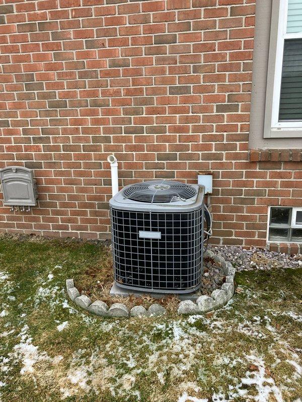 Conducted inspection of a 19-year-old furnace with failed secondary heat exchanger located in customer's basement. Documented existing outdoor AC unit positioned on gravel bed with decorative stone border adjacent to brick exterior wall. Photographed electrical service installation including four digital electric meters and associated junction boxes. Prepared comprehensive replacement options for furnace-only and complete furnace/AC system replacement as alternative to costly repairs on aging equipment.
